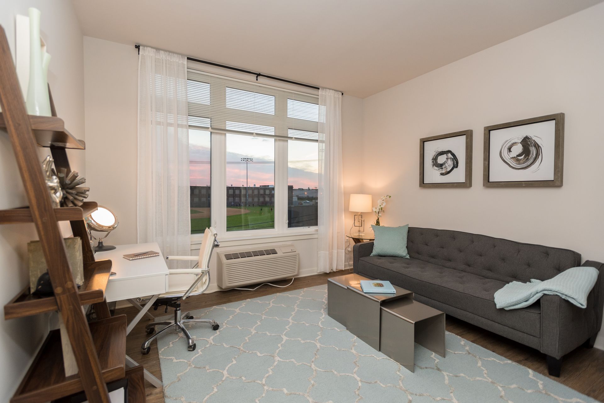 A living room with a couch , desk , chair and ladder.