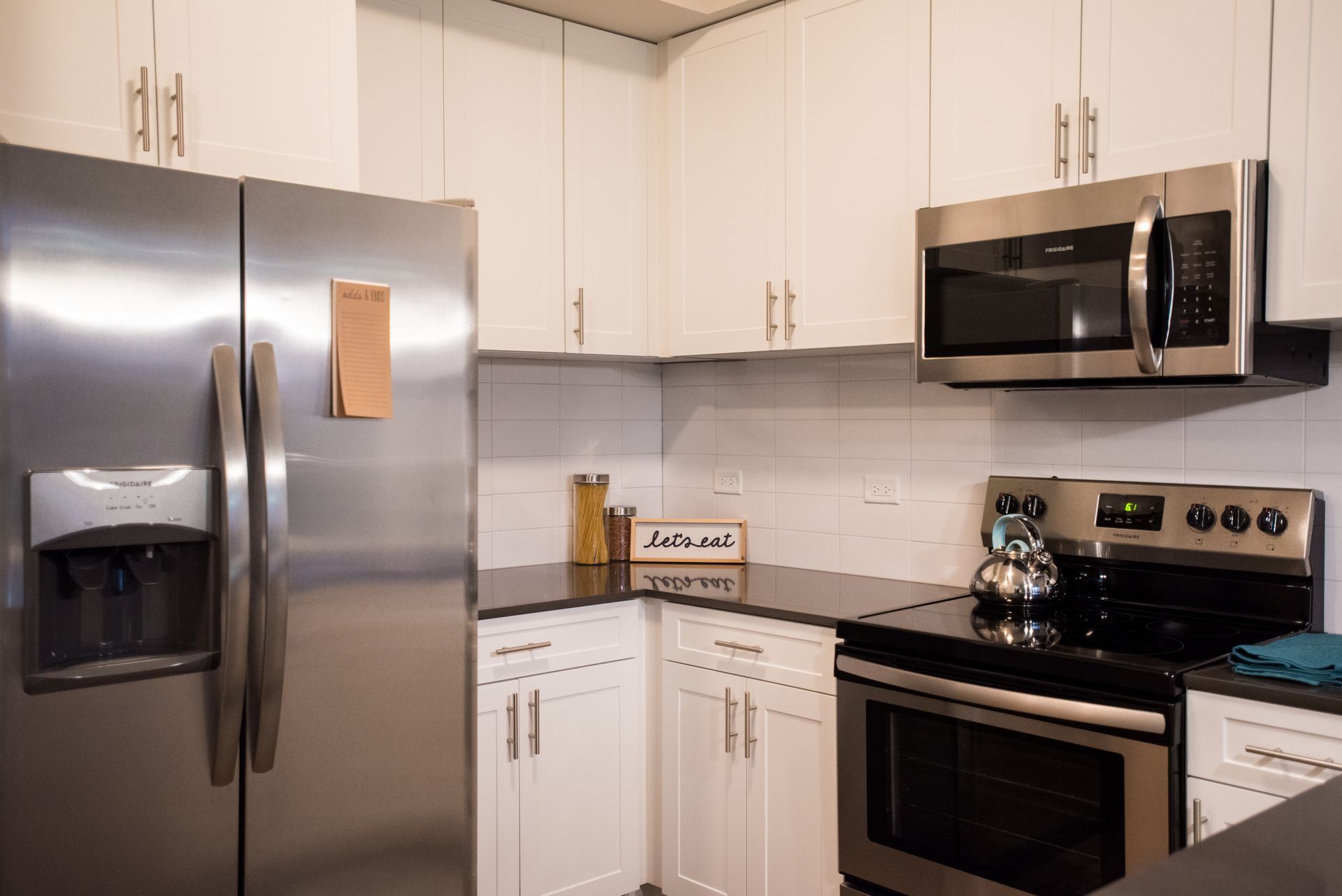 A kitchen with stainless steel appliances and white cabinets.