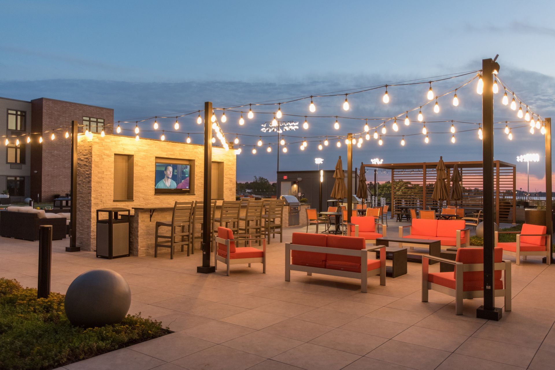 A patio area with a couch , chairs , tables and a television.