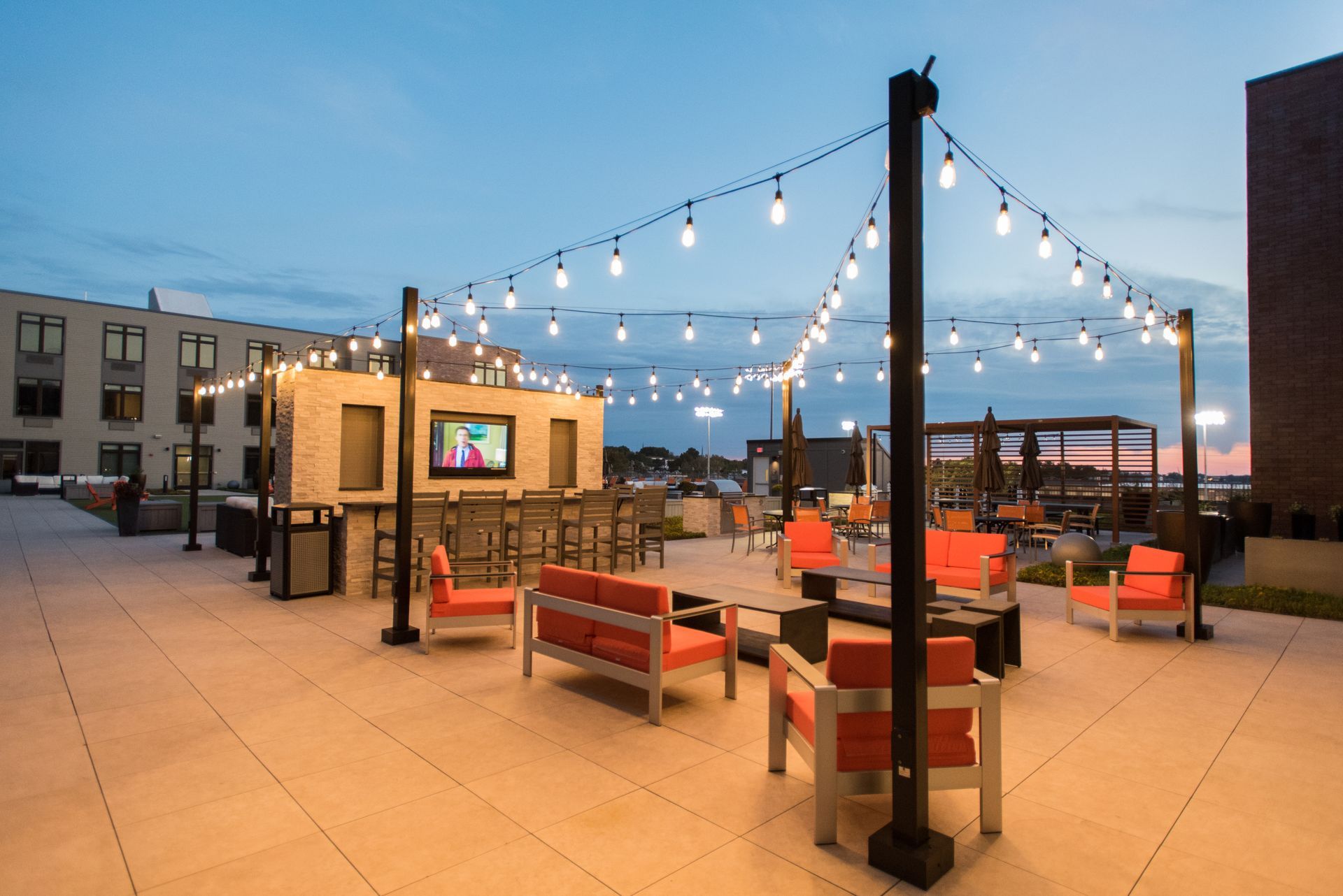 A patio with a couch , chairs , umbrellas and a television.