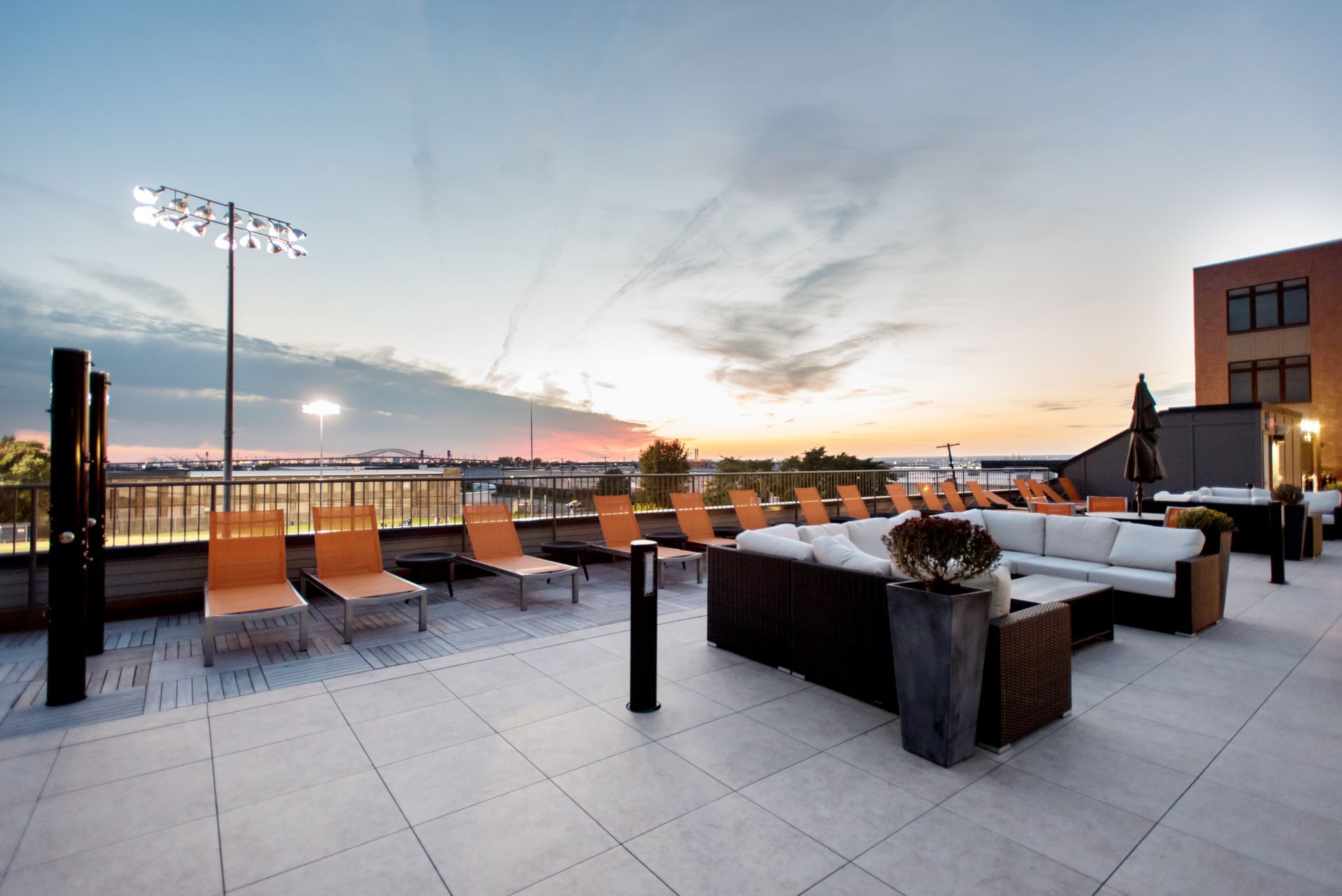 A rooftop patio with a couch and chairs at sunset