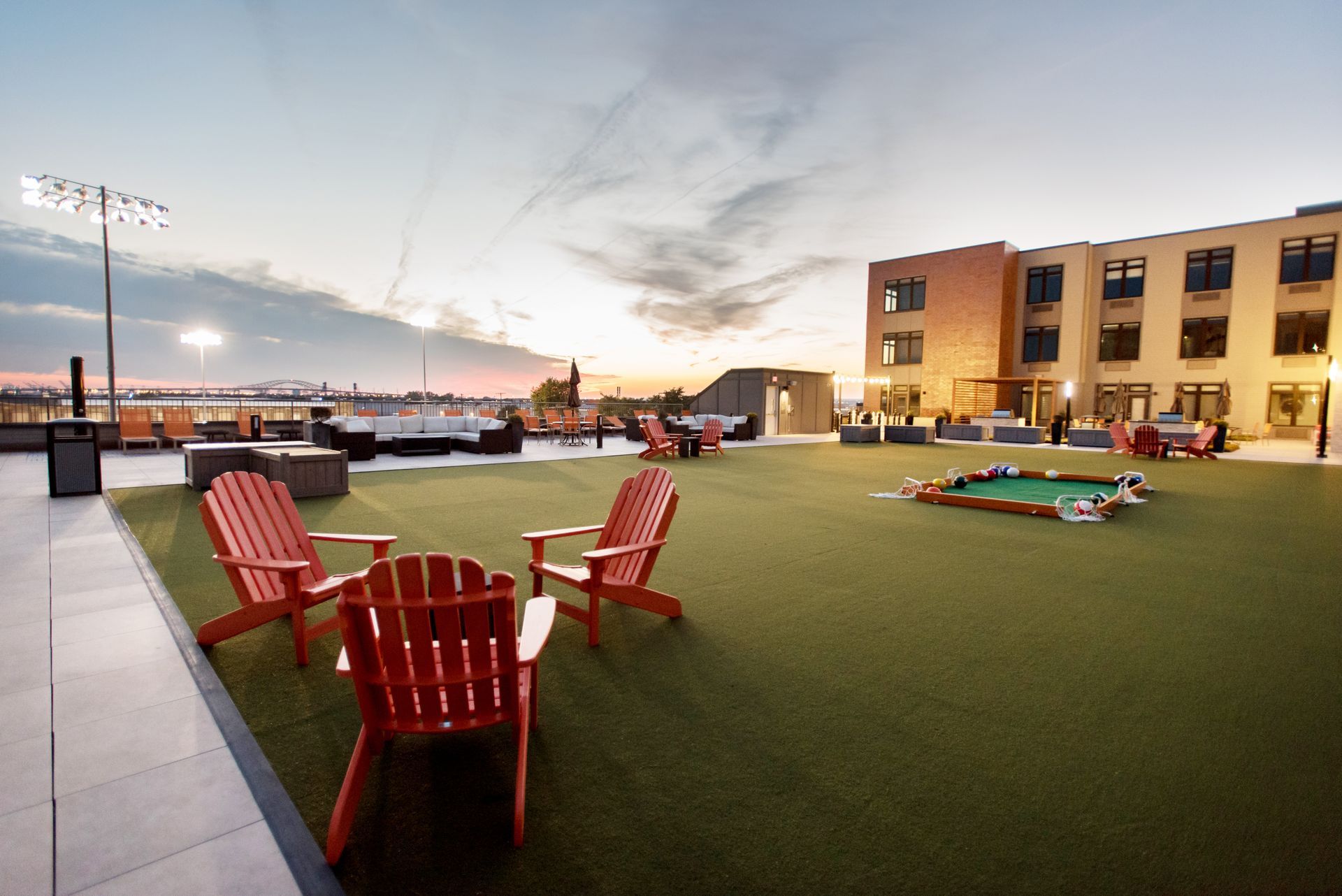 A lawn with red chairs and a pool table in front of a building.