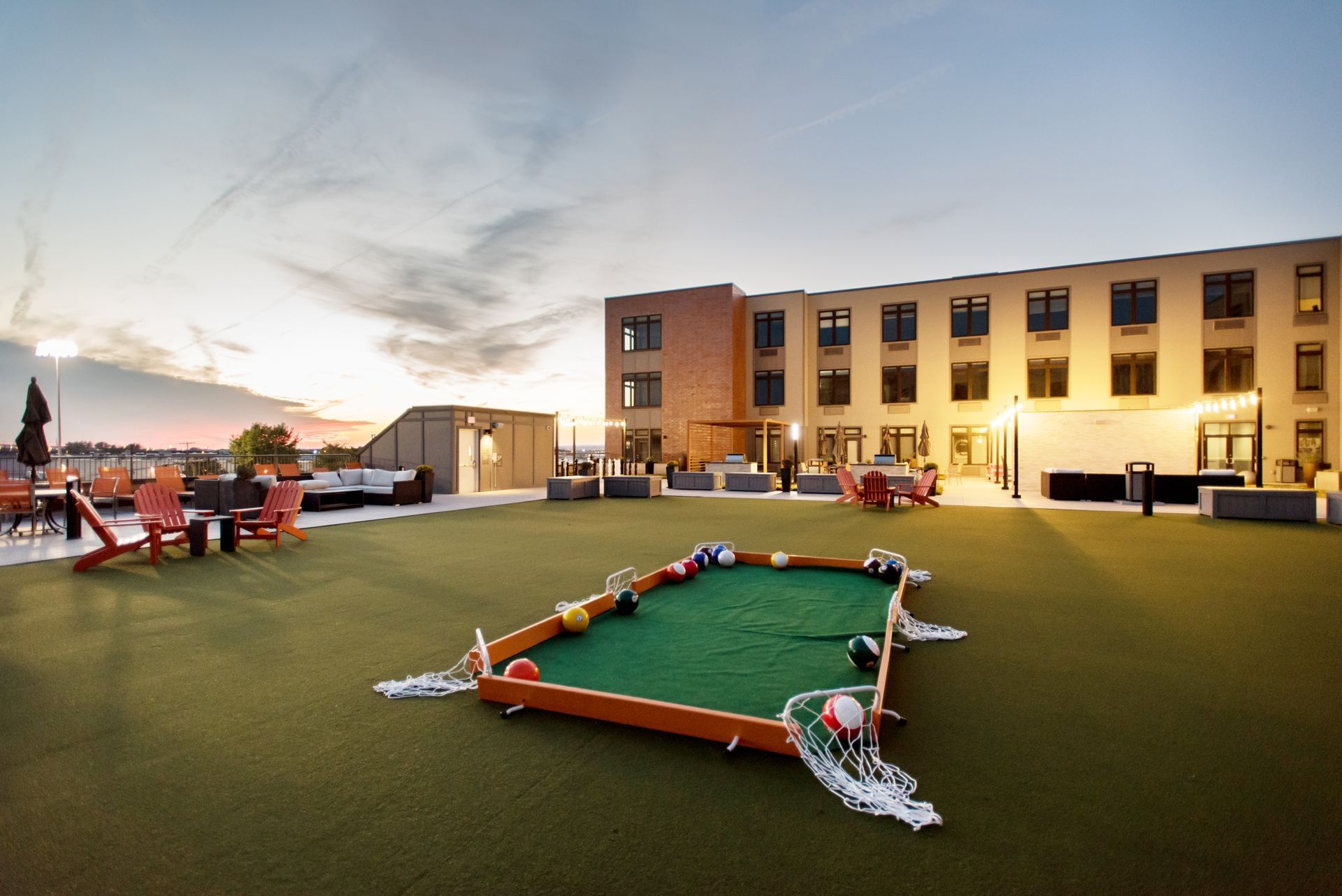 A pool table is sitting on the grass in front of a building.