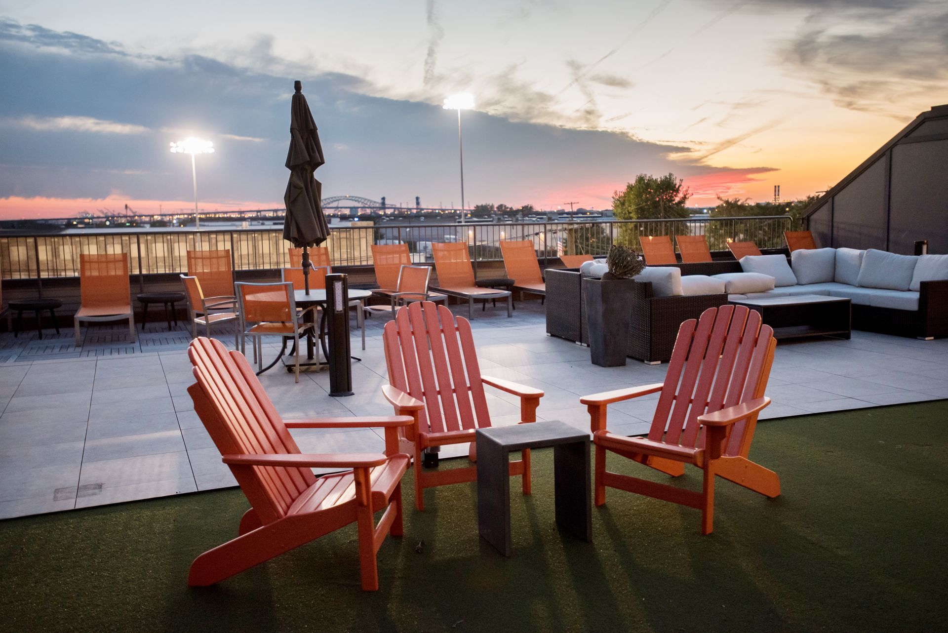 Two red adirondack chairs are sitting on a patio at sunset.