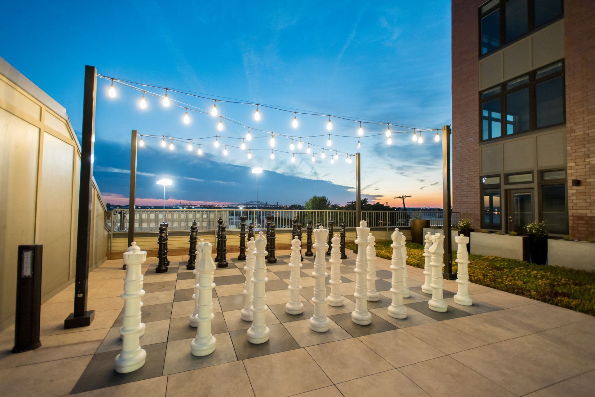 A large chess board is sitting on the sidewalk outside of a building.