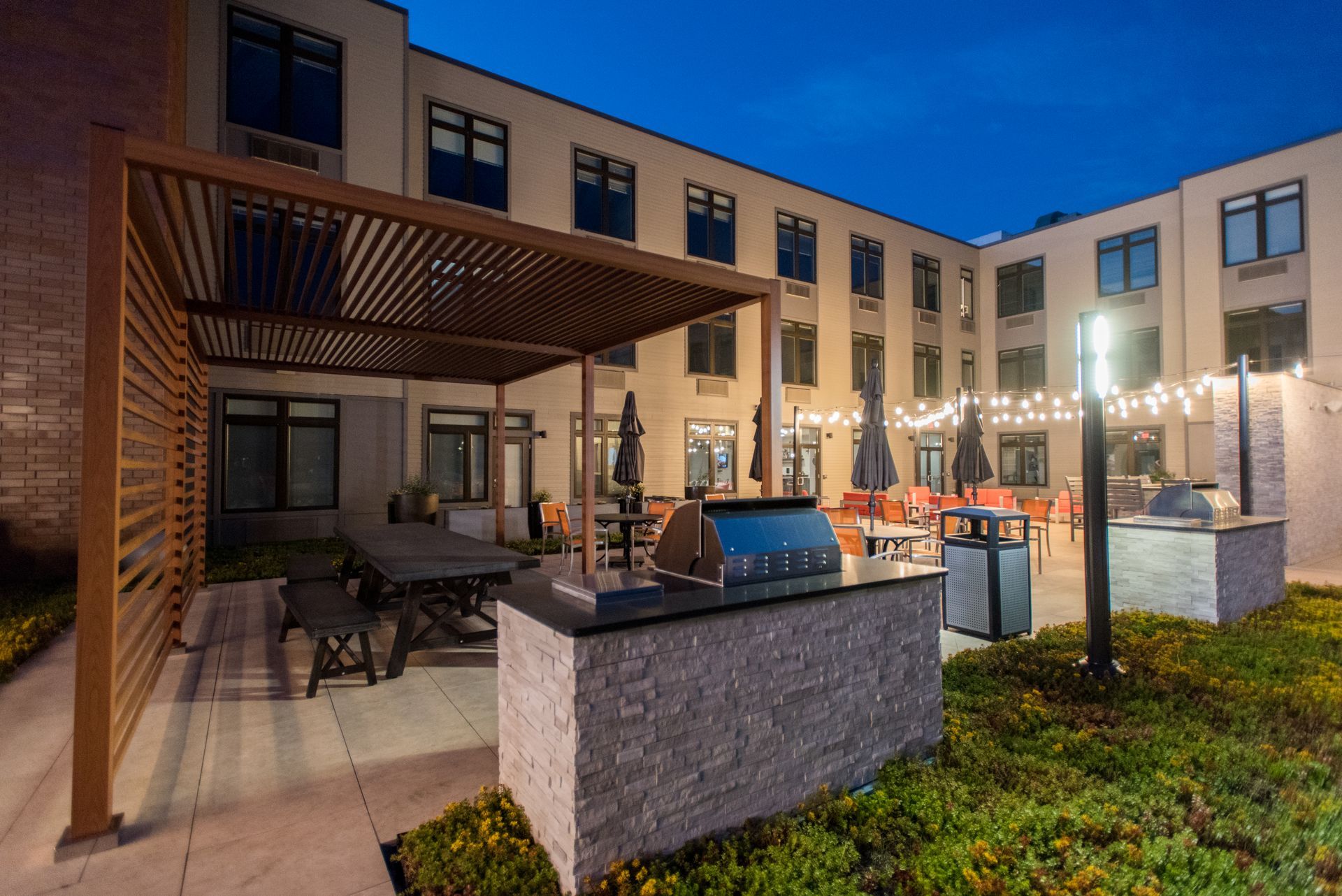 A large building with a pergola and a grill in front of it.