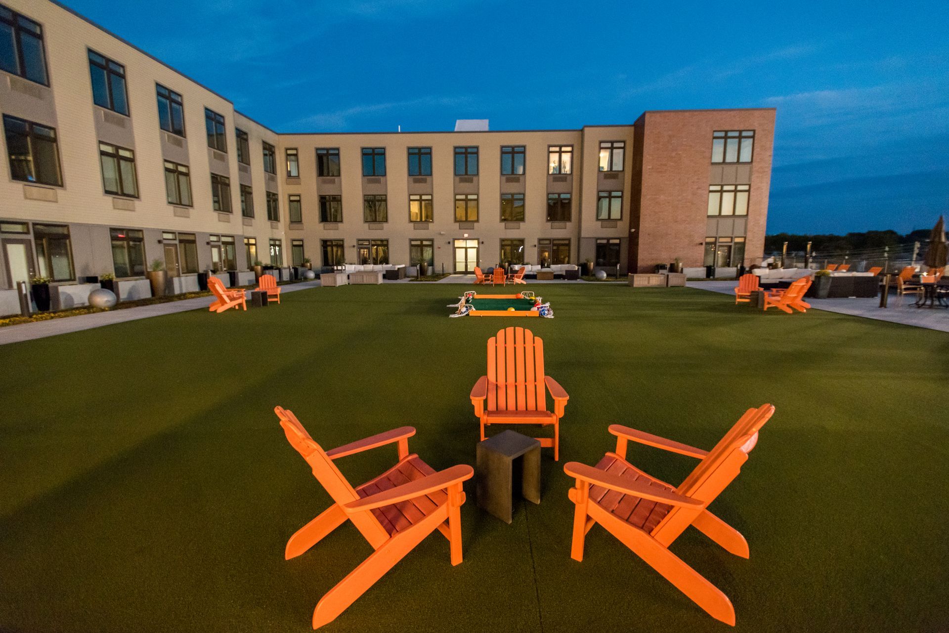 A lawn with chairs and tables in front of a building.