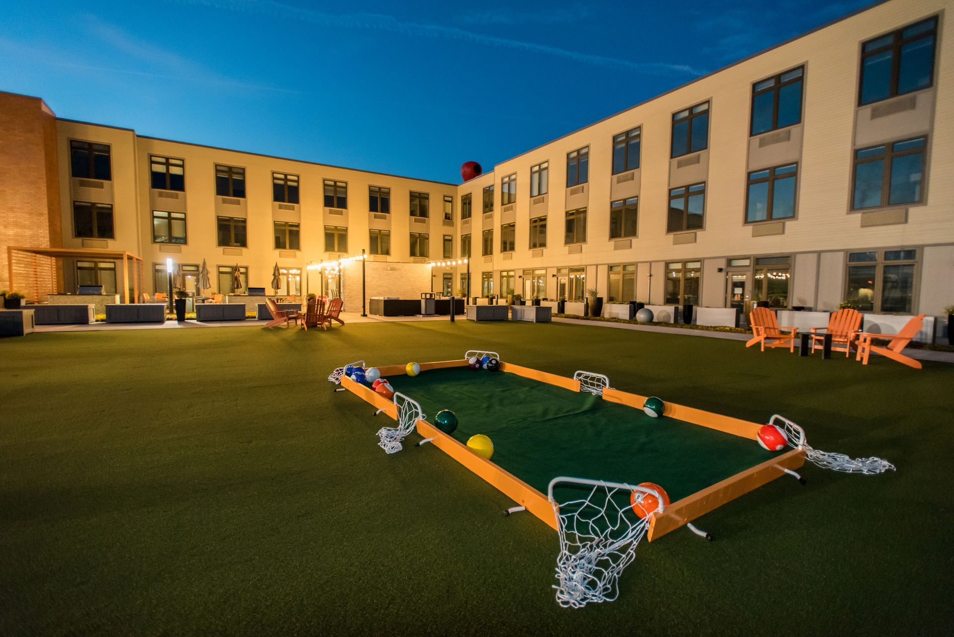 A pool table with balls and a basketball hoop in front of a building.
