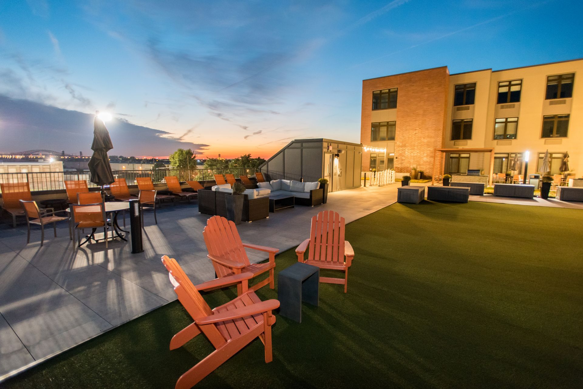 There are many chairs and tables on the roof of a building.