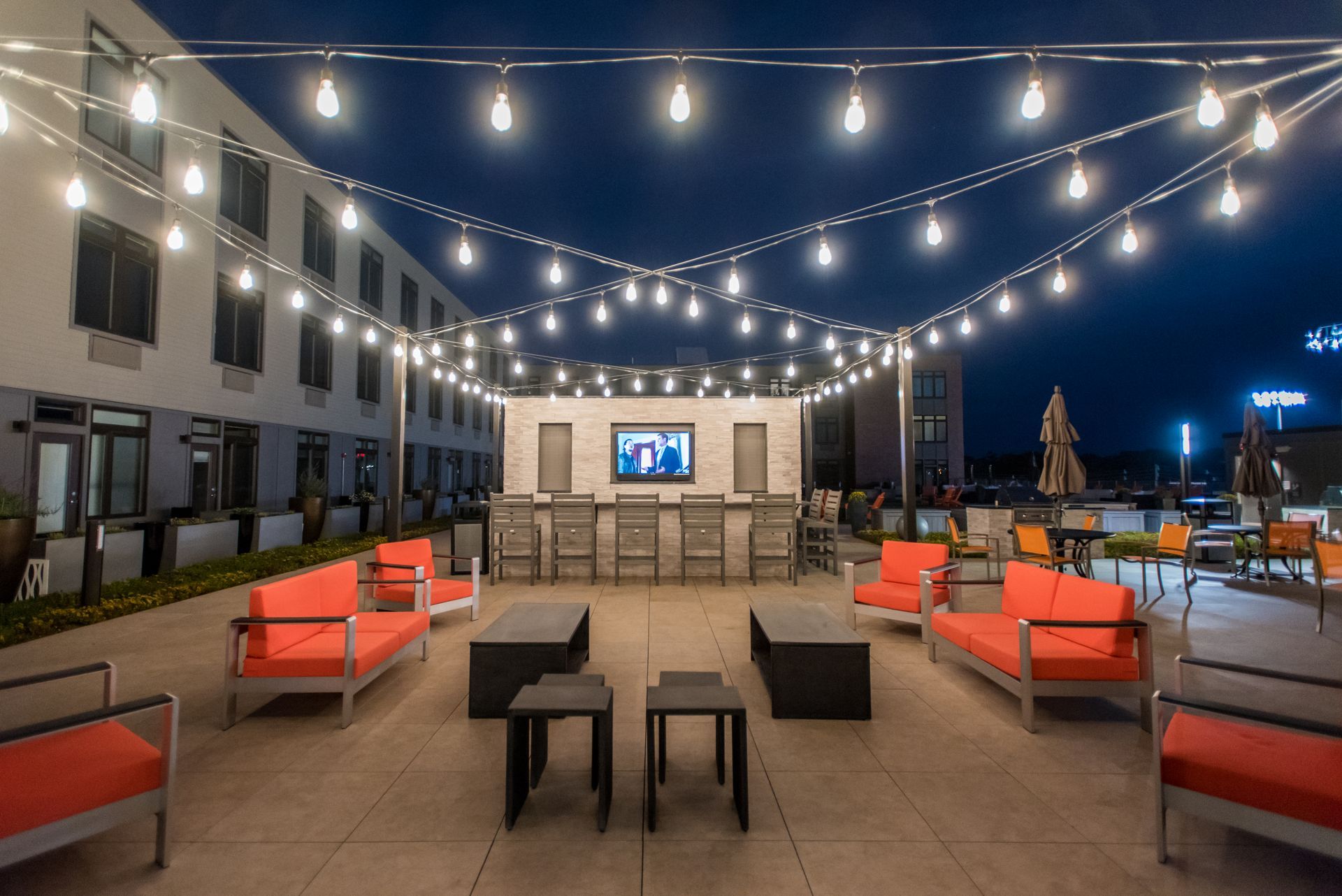A patio with a bar , tables , chairs and a television.
