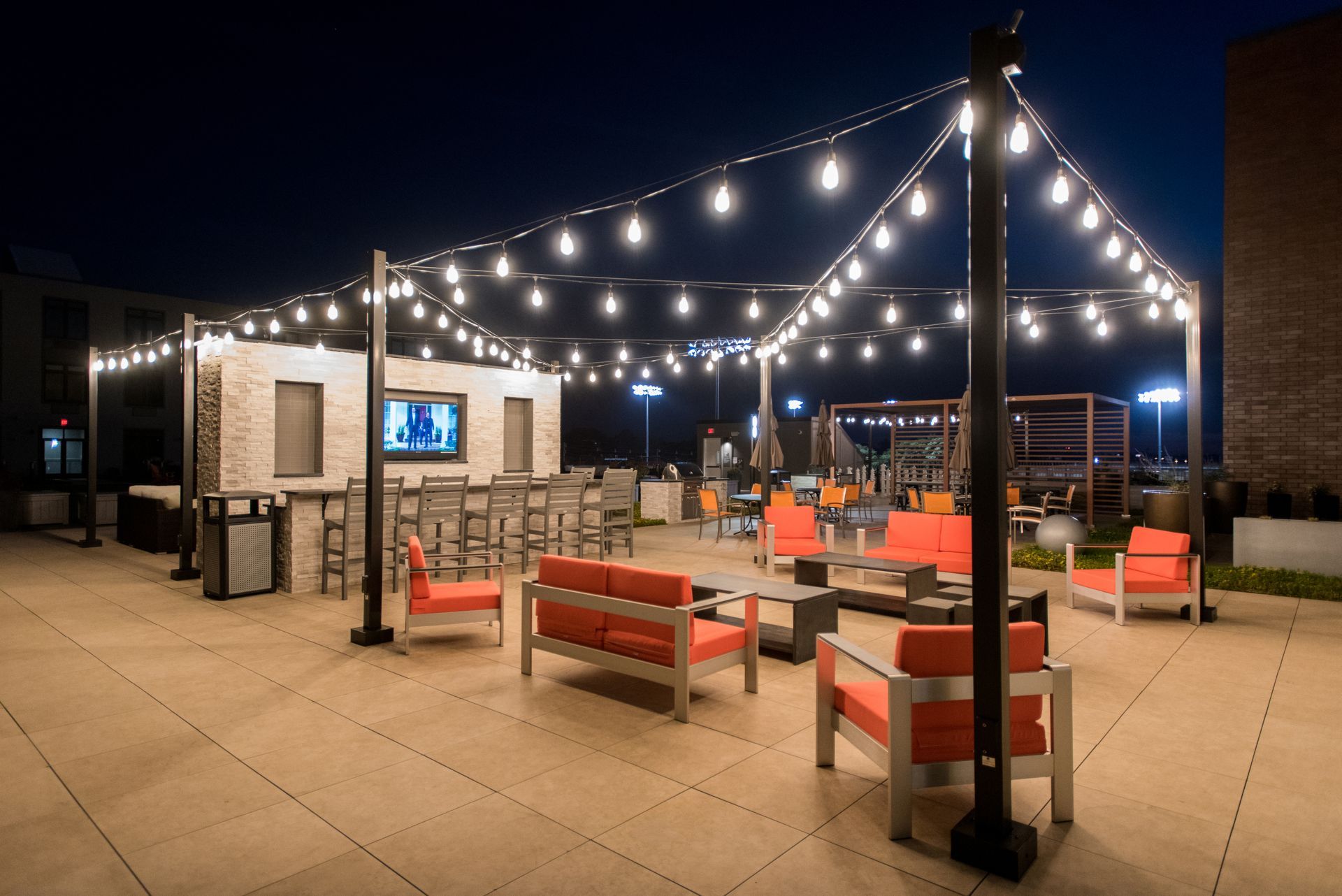 A patio with a lot of furniture and lights at night.