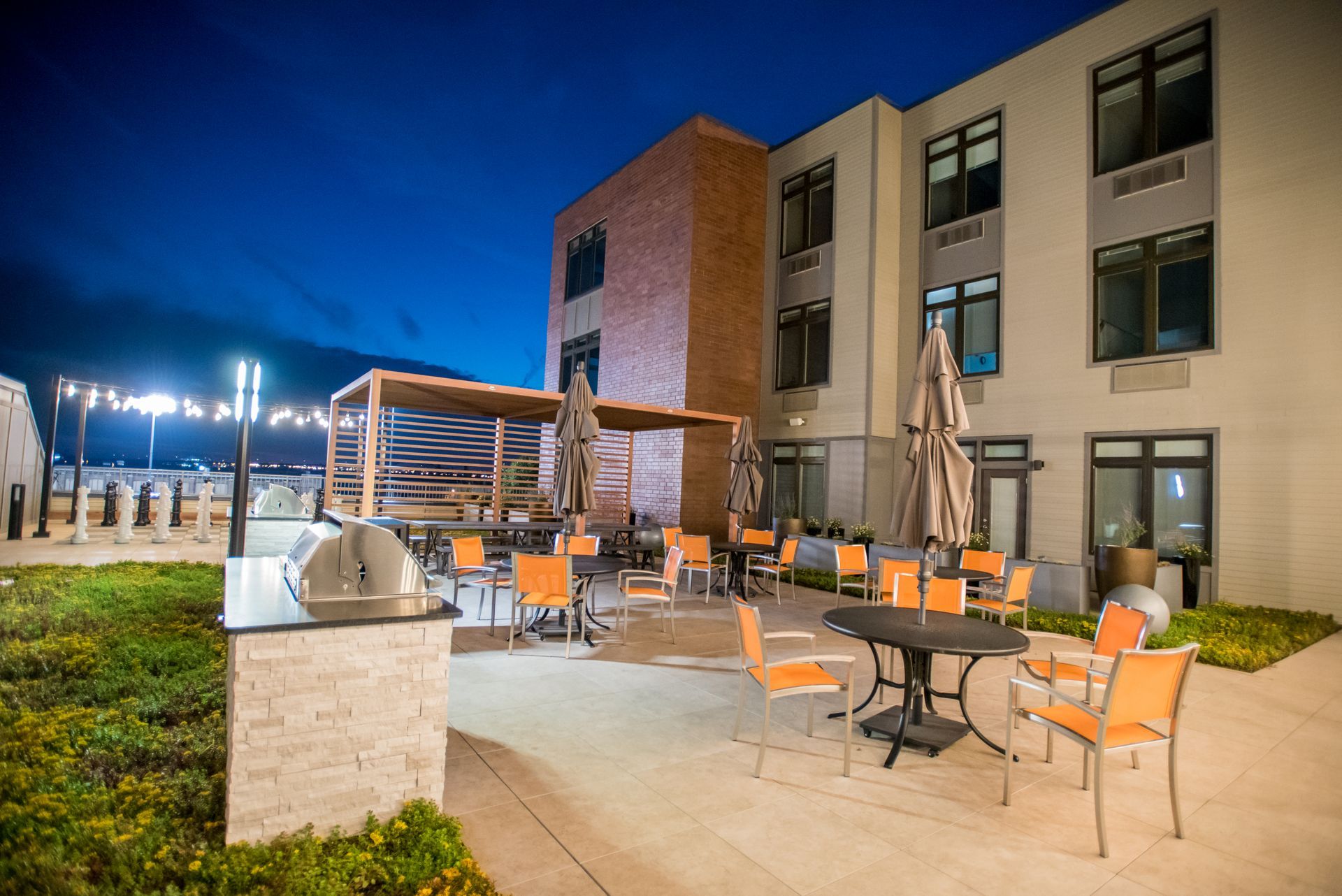 A large building with tables and chairs in front of it at night.