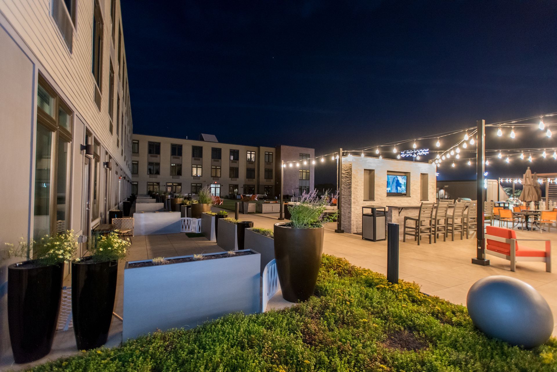 A patio area with tables and chairs in front of a building at night.