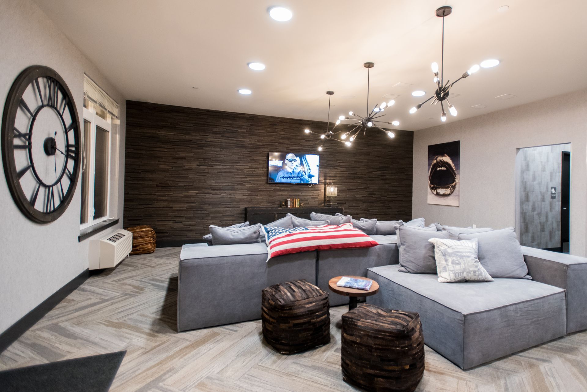 A living room with a couch , ottomans , and a clock on the wall.