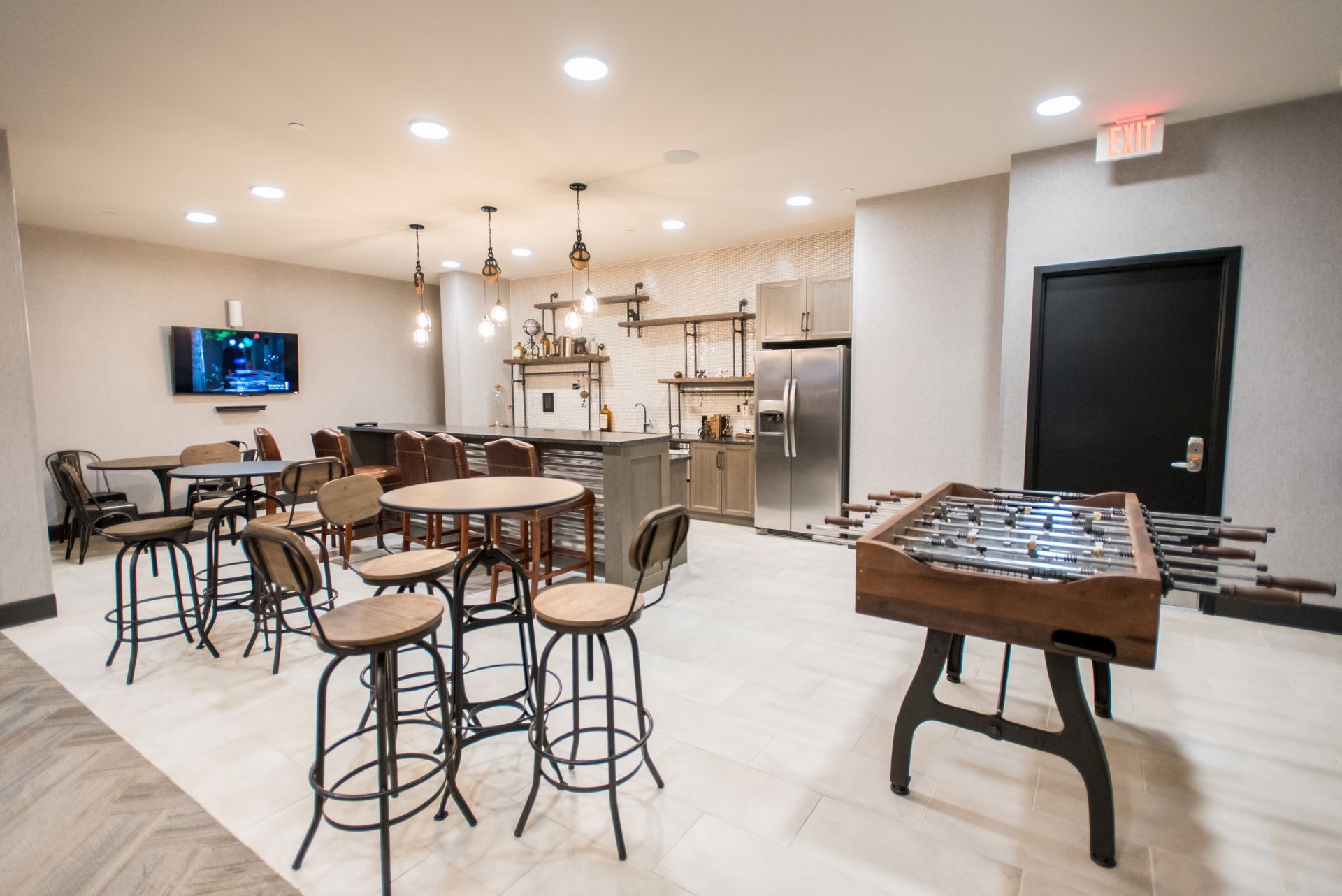 A game room with tables and chairs and a foosball table.
