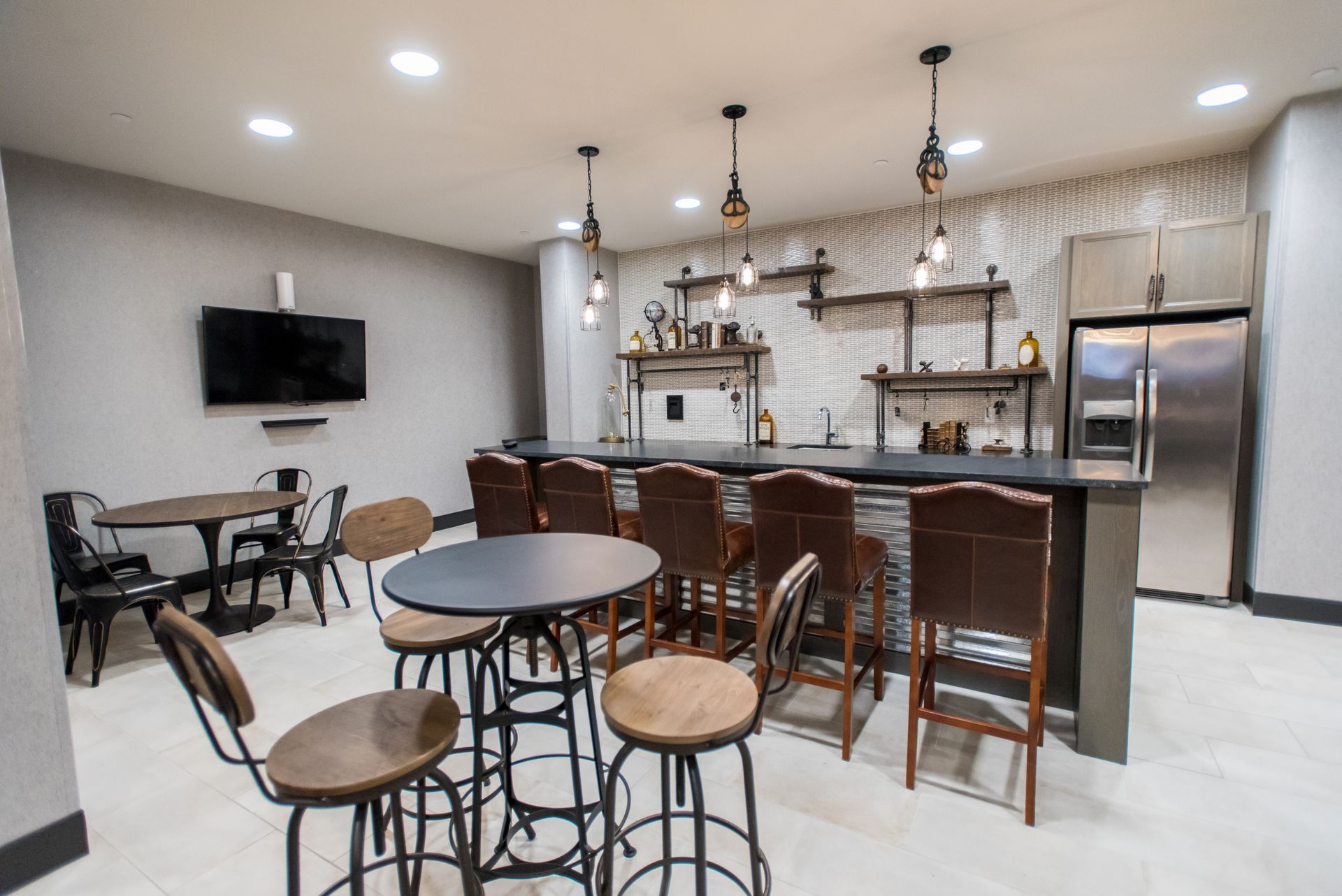 A room with tables and chairs and a bar.