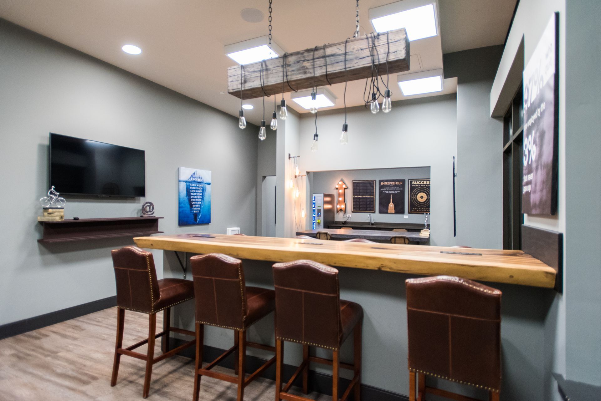 A room with a long wooden table and chairs and a flat screen tv.