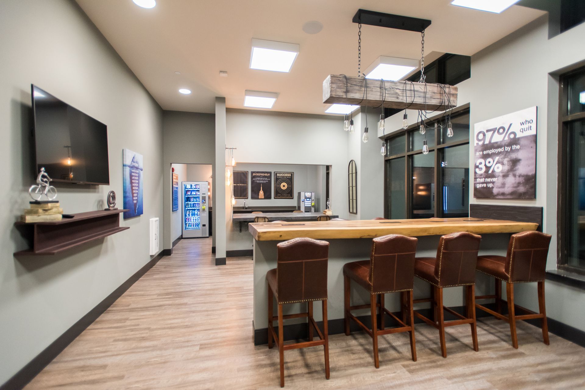 A large room with a bar and stools and a flat screen tv.