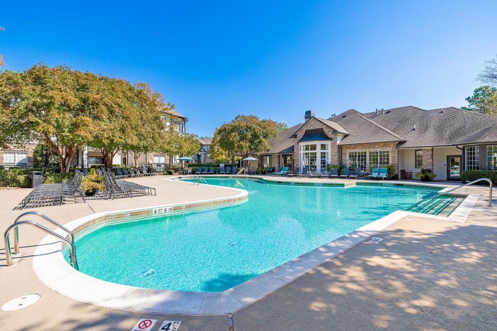 a large swimming pool with the clubhouse in the background at Marquis Carmel Commons in Charlotte, NC.