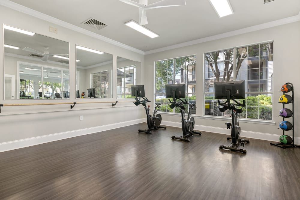 a gym with a lot of windows and exercise bikes at Marquis Carmel Commons in Charlotte, NC.