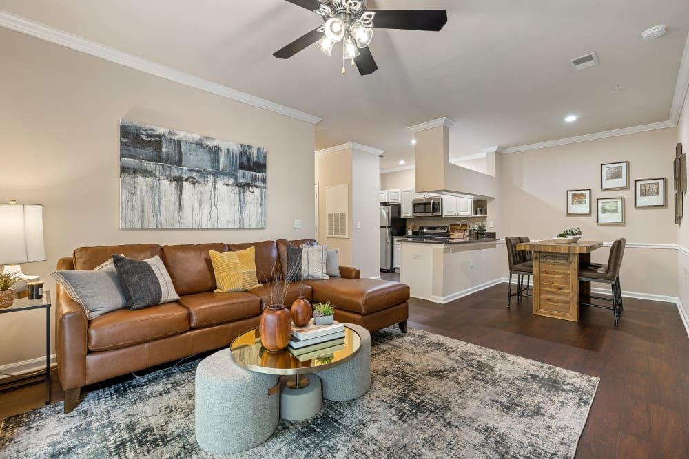 a living room with a brown couch, coffee table, and ceiling fan at Marquis Carmel Commons in Charlotte, NC.