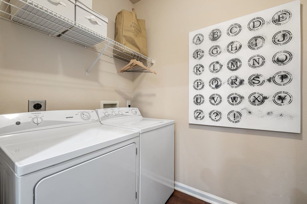 a laundry room with a washer and dryer and a painting on the wall at Marquis Carmel Commons in Charlotte, NC.