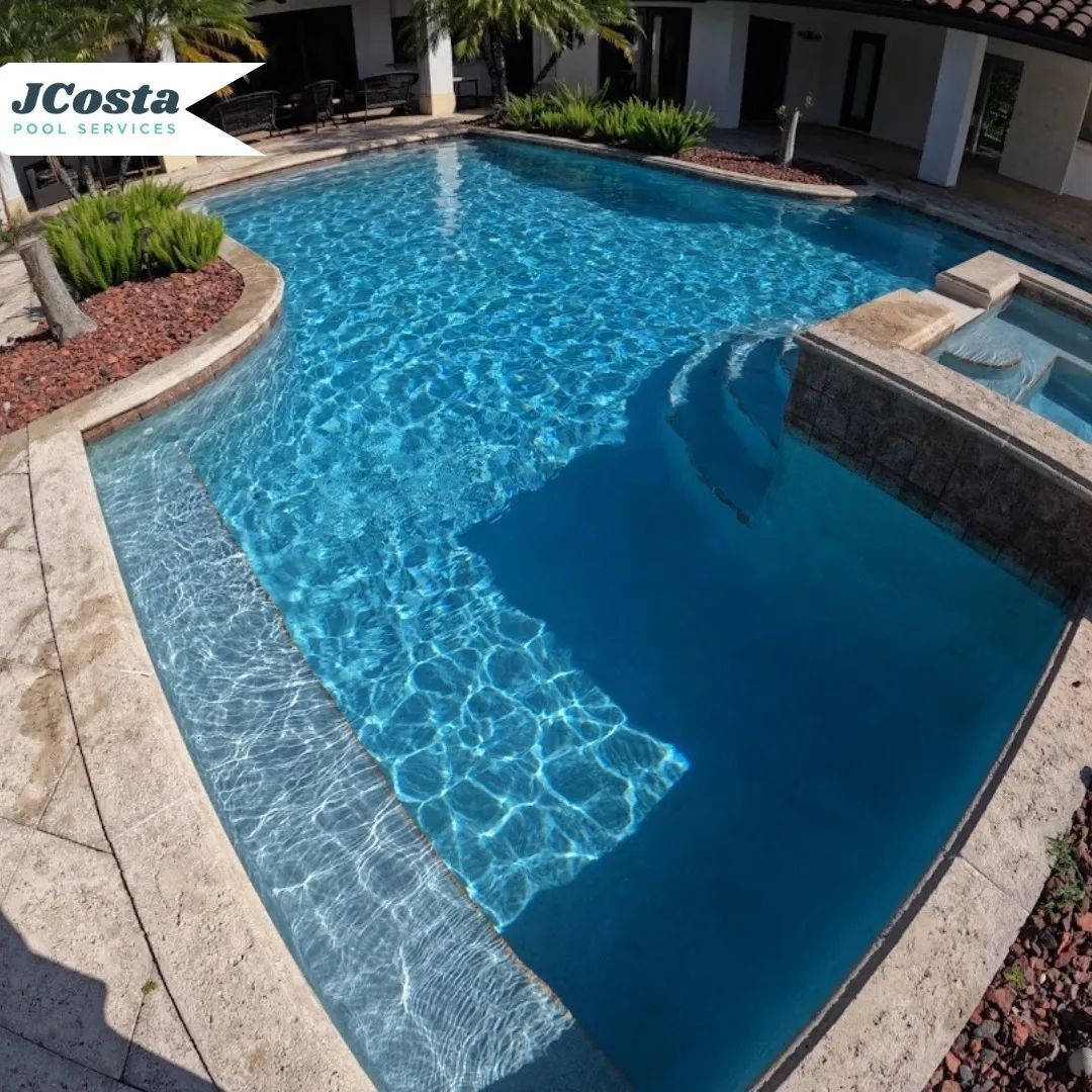 Blue swimming pool with attached spa; stone and landscaped setting.