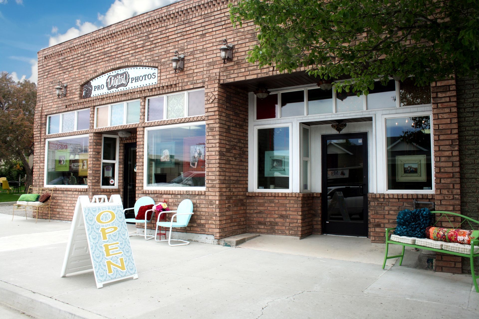 An outdoor image of our store Pro Digital Photos with an open sign and benches and chairs.