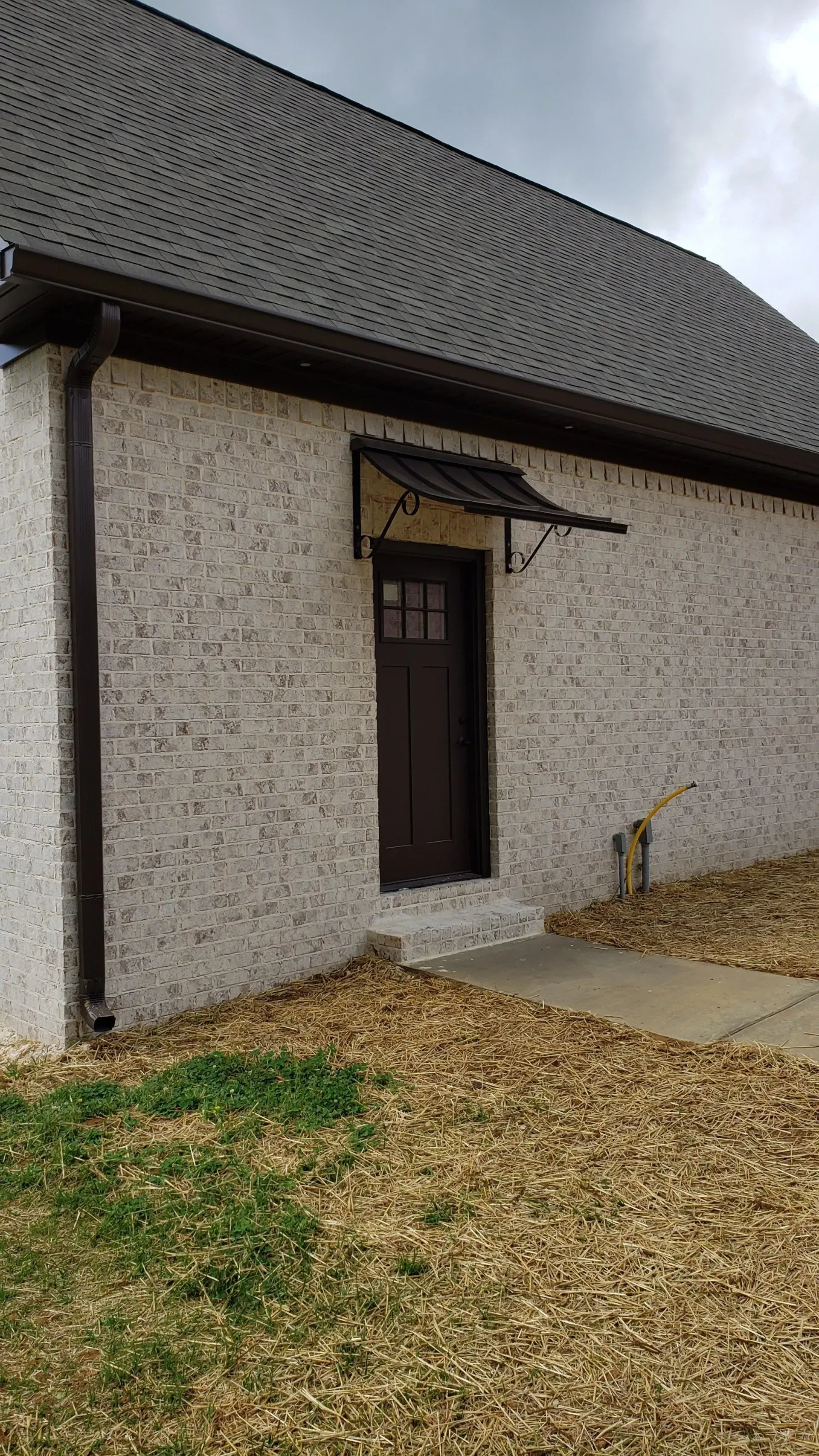 White Brick Building with Brown Door — Decatur, AL — Evans Awnings