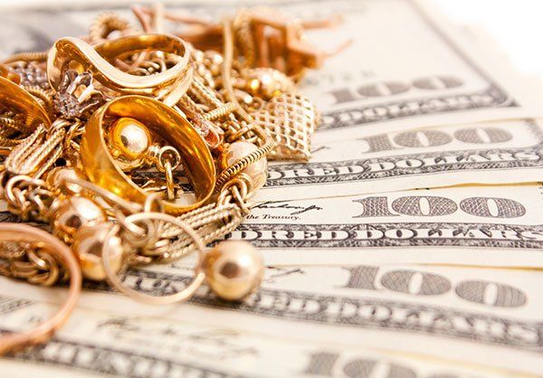 pile of gold jewelry on hundred dollar bills