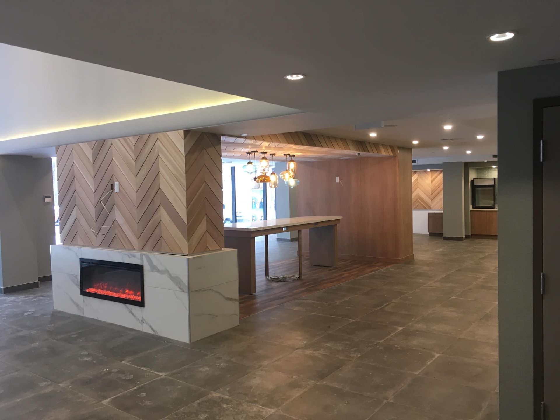 Hall d'entrée moderne avec cheminée en pierre, murs lambrissés et sol carrelé sous éclairage encastré