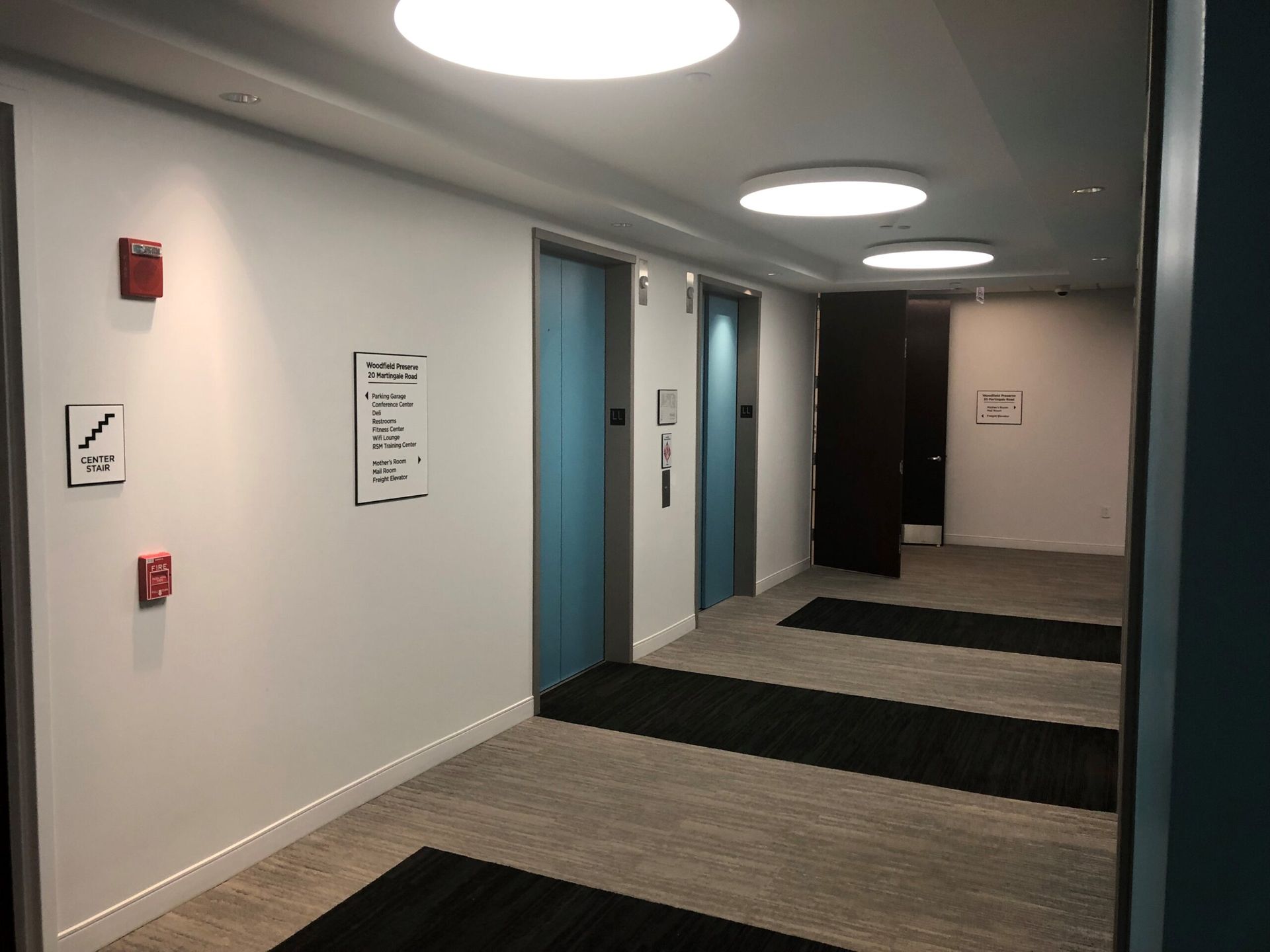 A hallway with two elevators and a fire extinguisher on the wall.