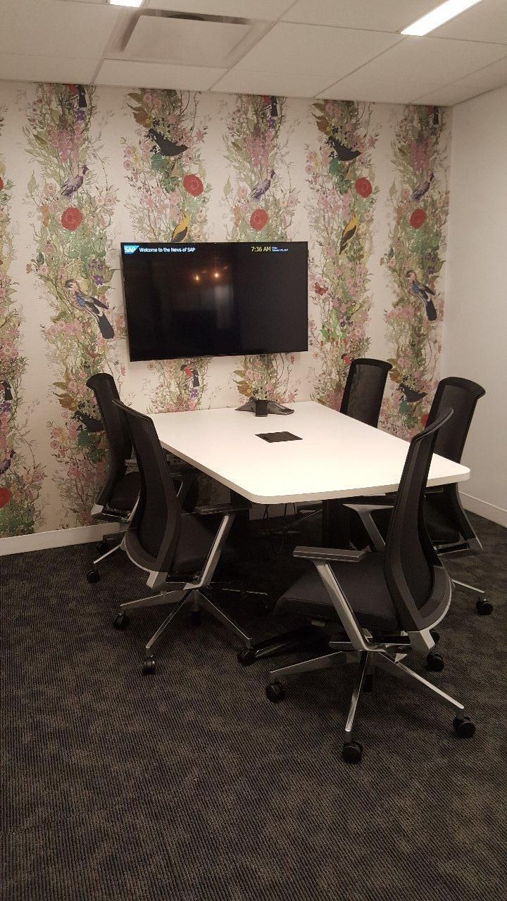 A conference room with a table and chairs and a flat screen tv on the wall.