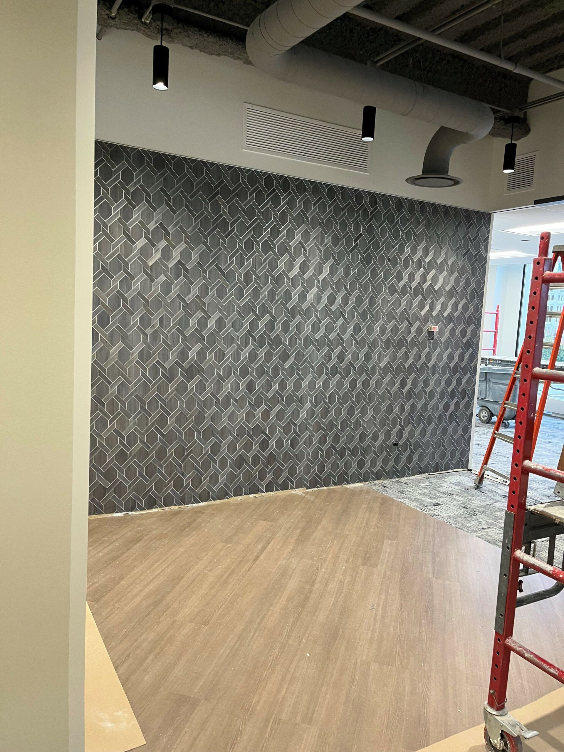 A room with a ladder and a wall with a pattern on it