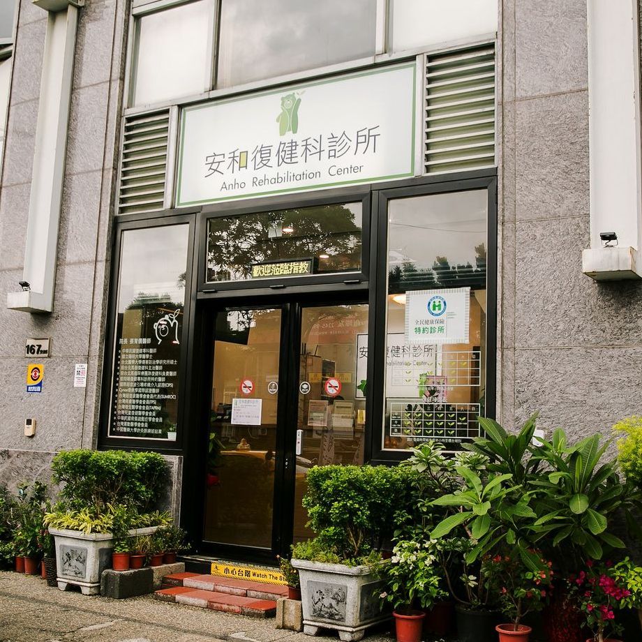 安和復健科診所的入口處有玻璃門和中文招牌。入口處擺放著盆栽。