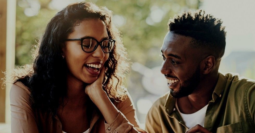 A man and a woman are laughing together while sitting at a table.