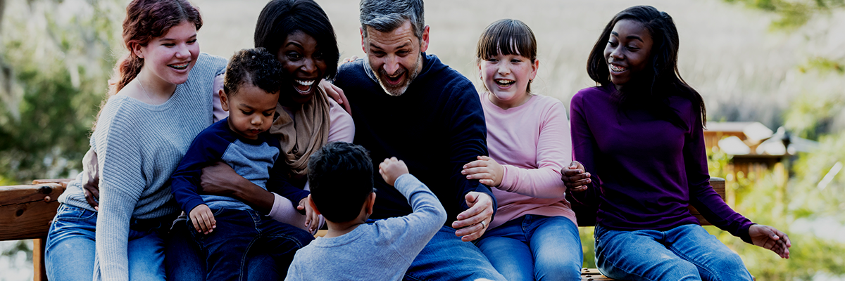 A group of people are sitting on a bench with their children.