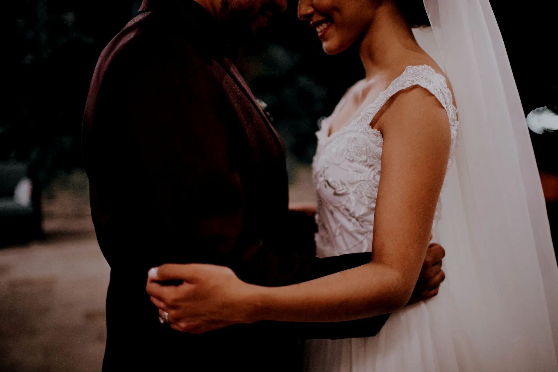 A bride and groom are hugging each other on their wedding day.