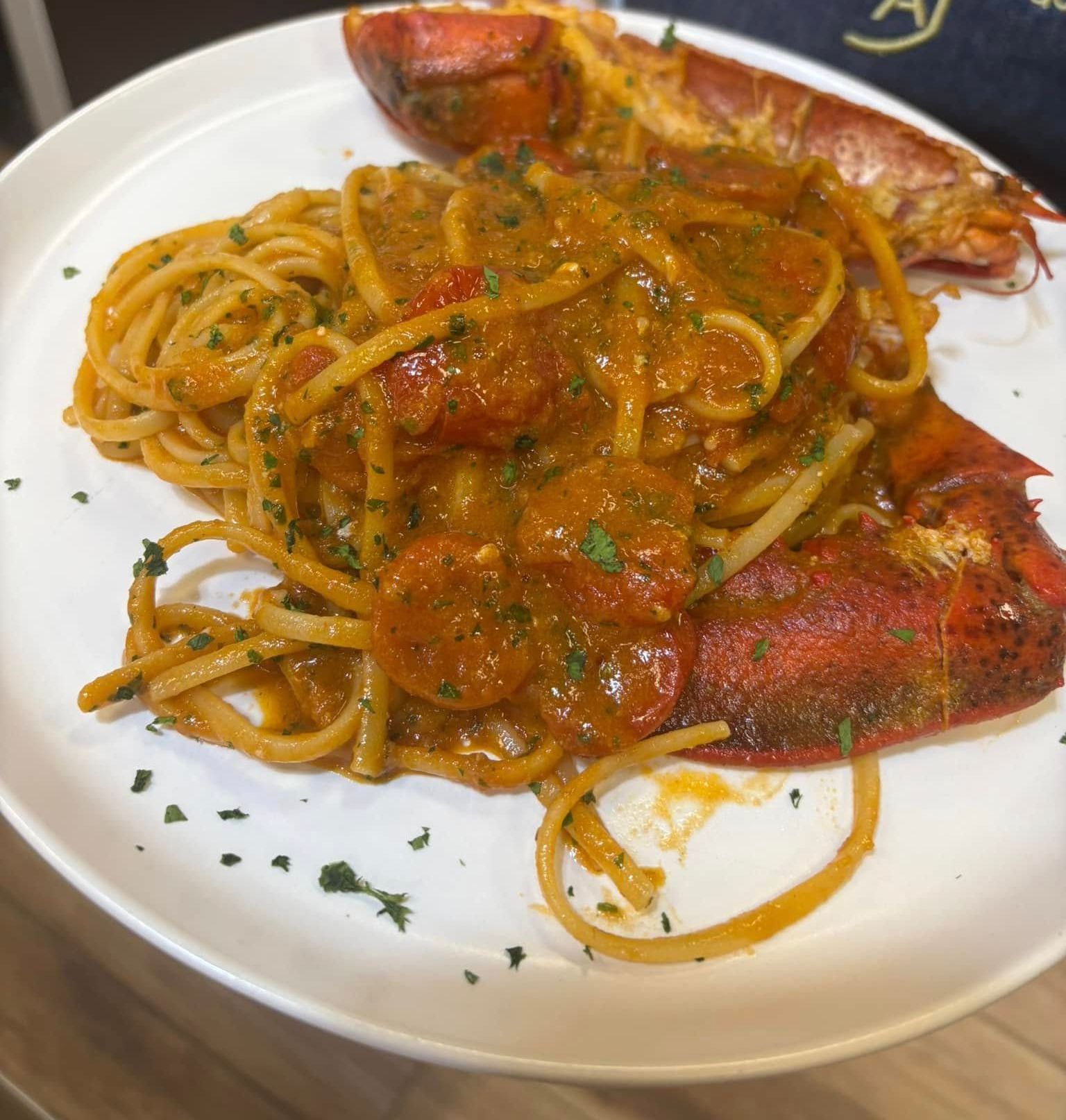 Un piatto bianco con sopra spaghetti e aragosta.