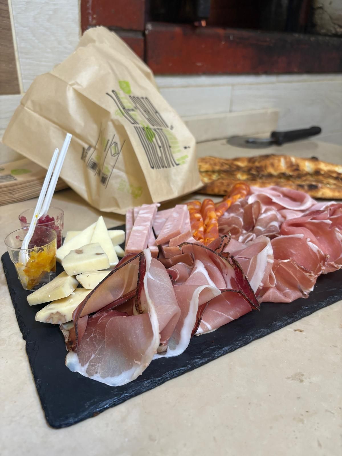 Un vassoio di carne e formaggio su un tavolo con una borsa sullo sfondo.