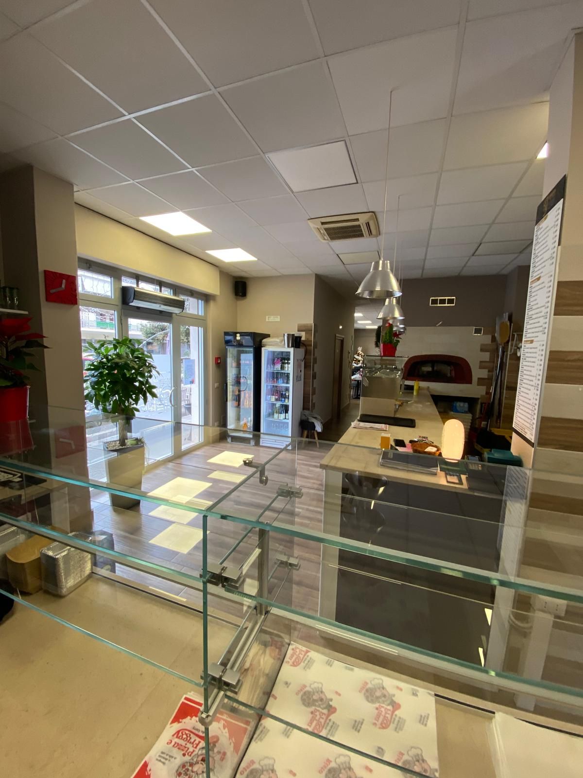 Una grande stanza con una ringhiera in vetro e un forno per pizza sullo sfondo.