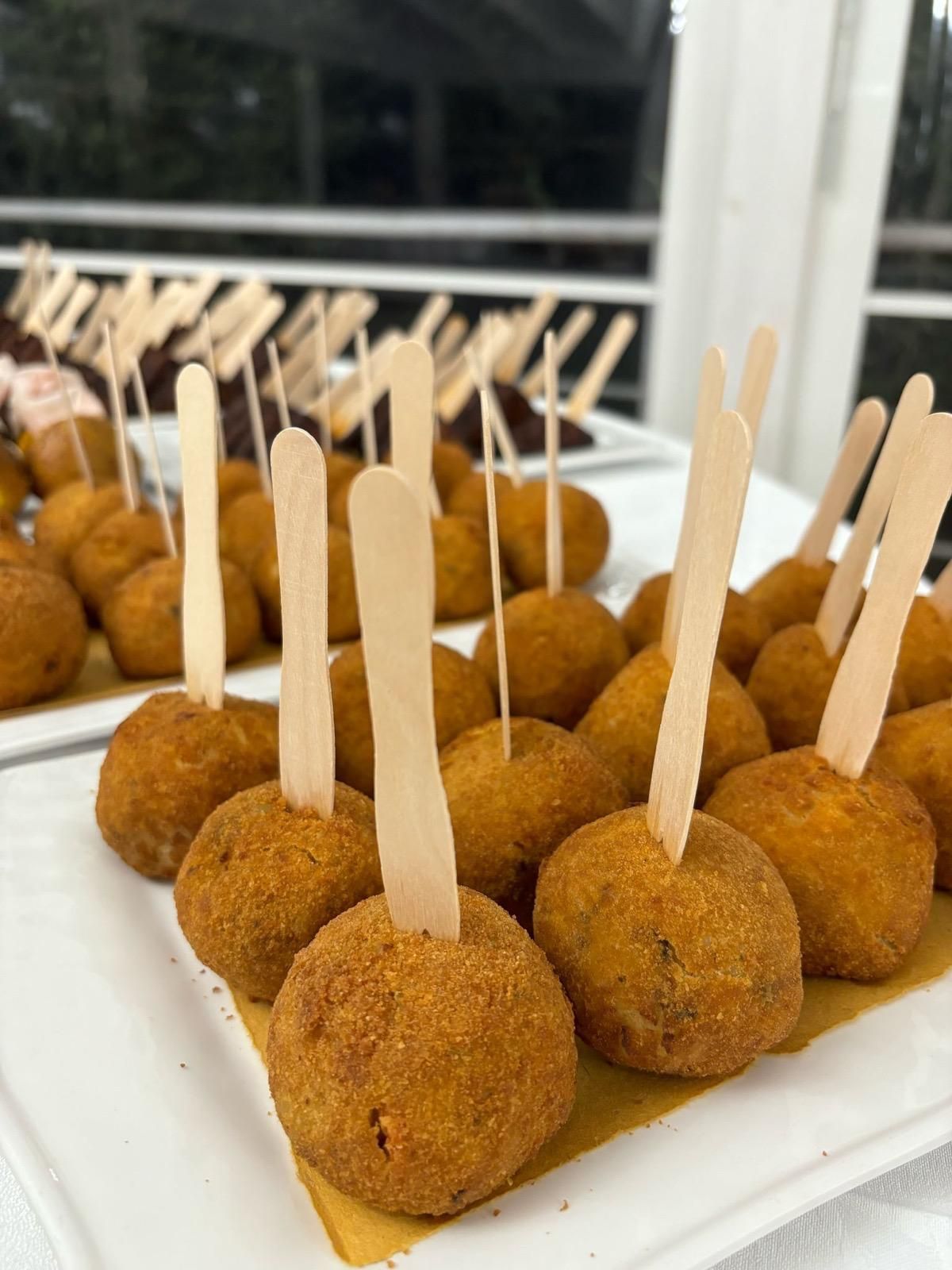 Un piatto bianco sormontato da cibo fritto su bastoncini di legno