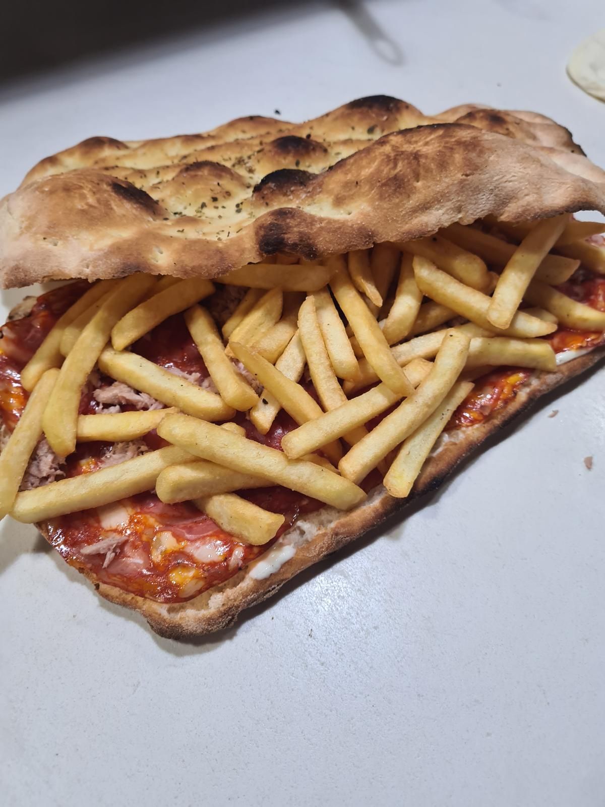 Una pizza con patatine fritte sopra