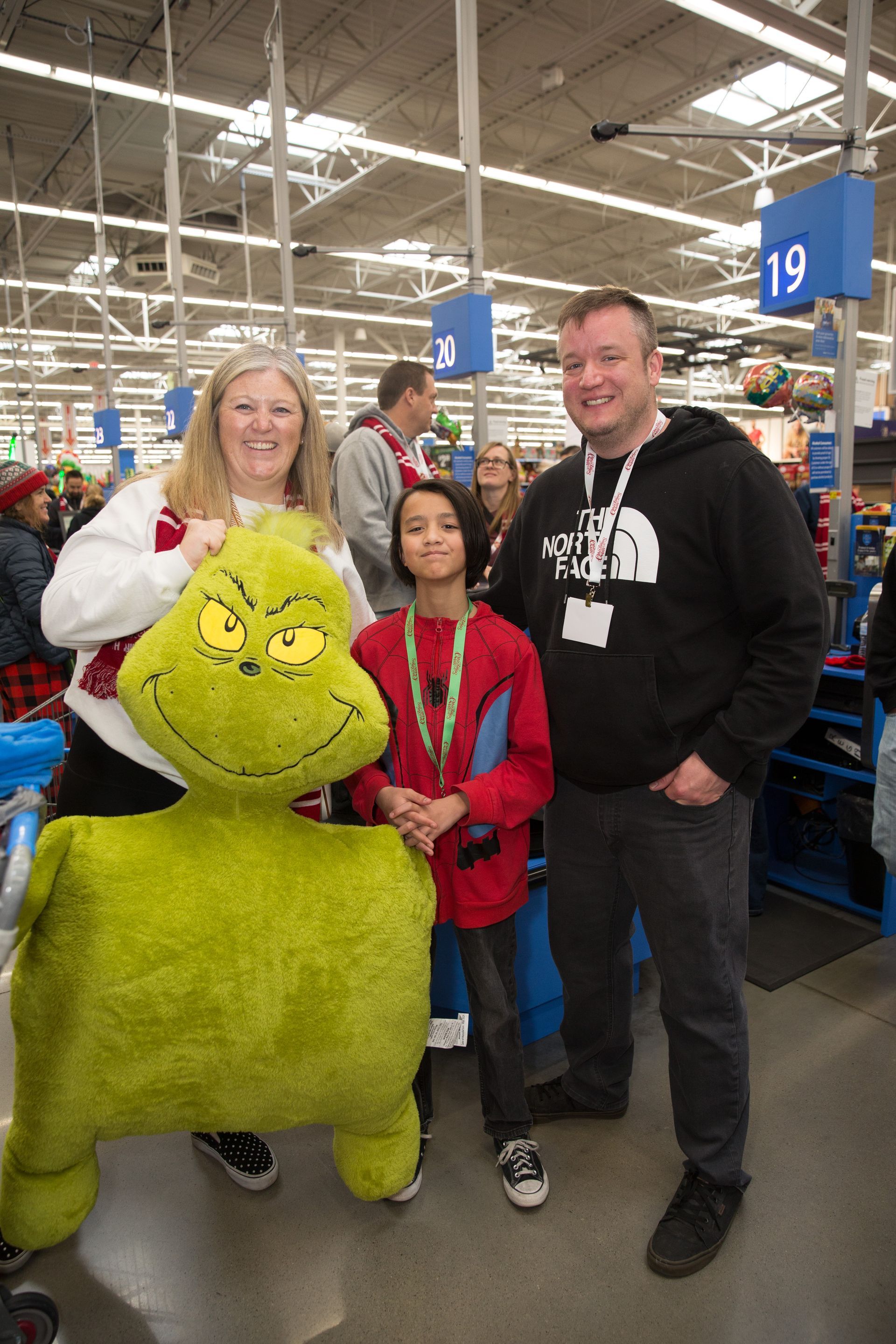 A family is posing for a picture with a grinch stuffed animal in a store.