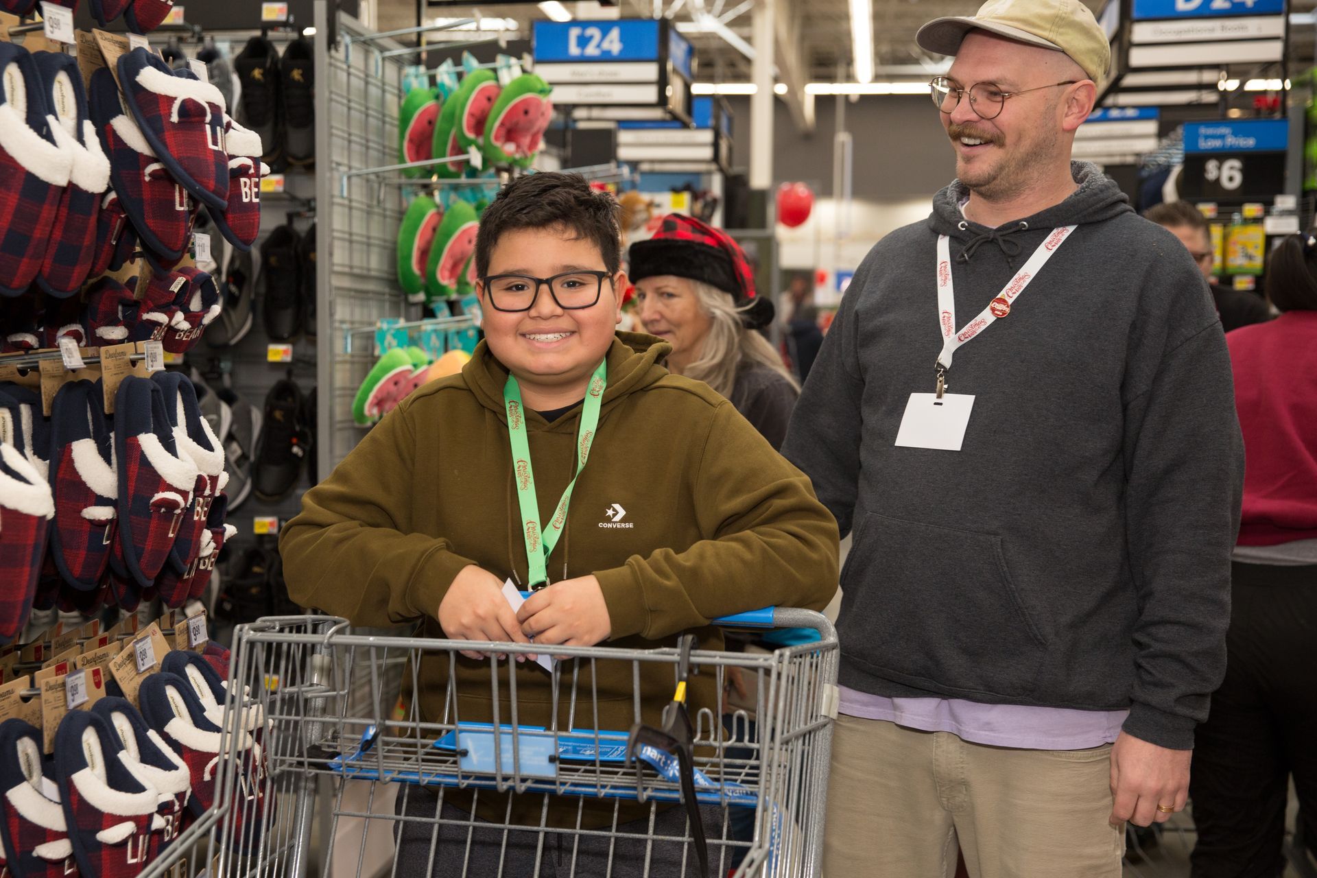 A man and a boy are standing next to a shopping cart in a store.