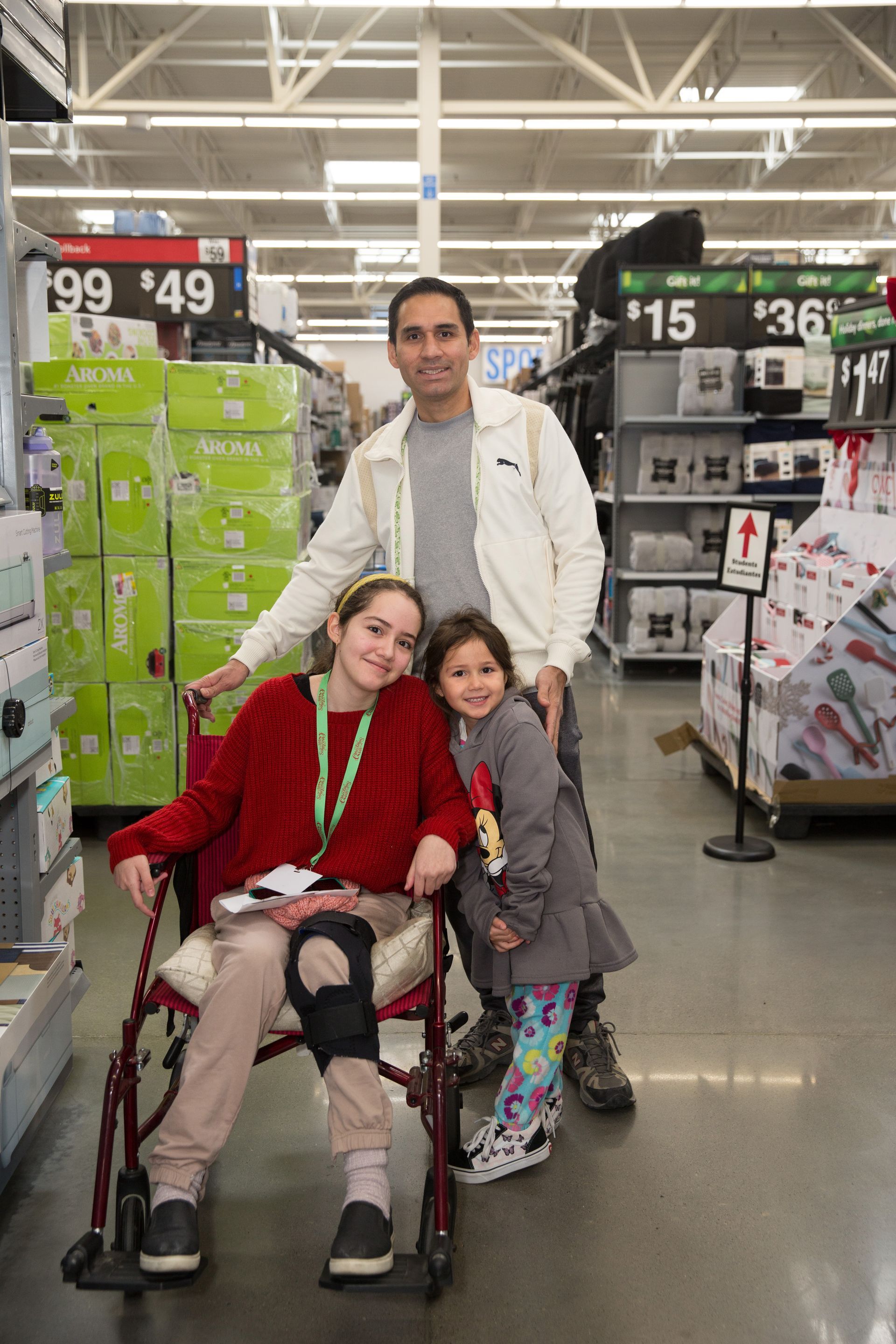 A man is standing next to a girl in a wheelchair in a store.