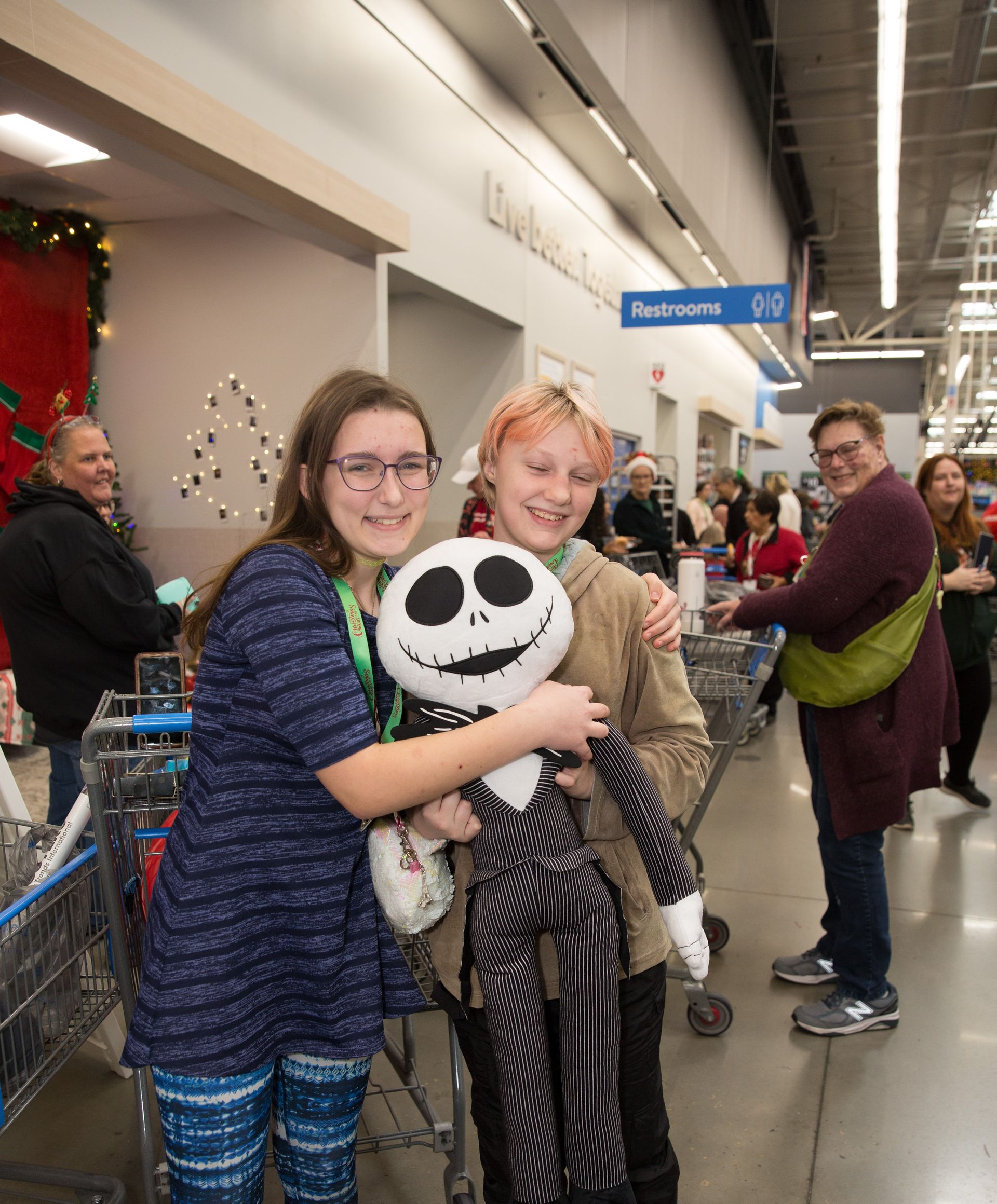 Two girls are holding a stuffed skeleton in a store.