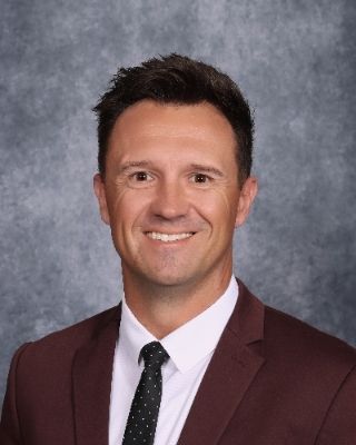 A man is wearing a red christmas suit and a white turtleneck.