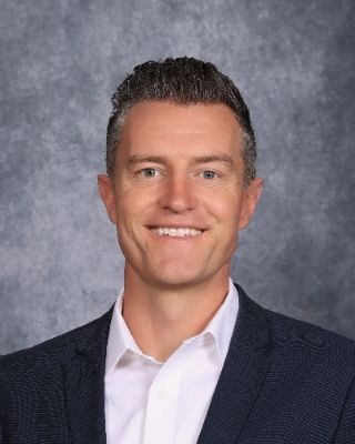 A man in a suit and tie is smiling for the camera.