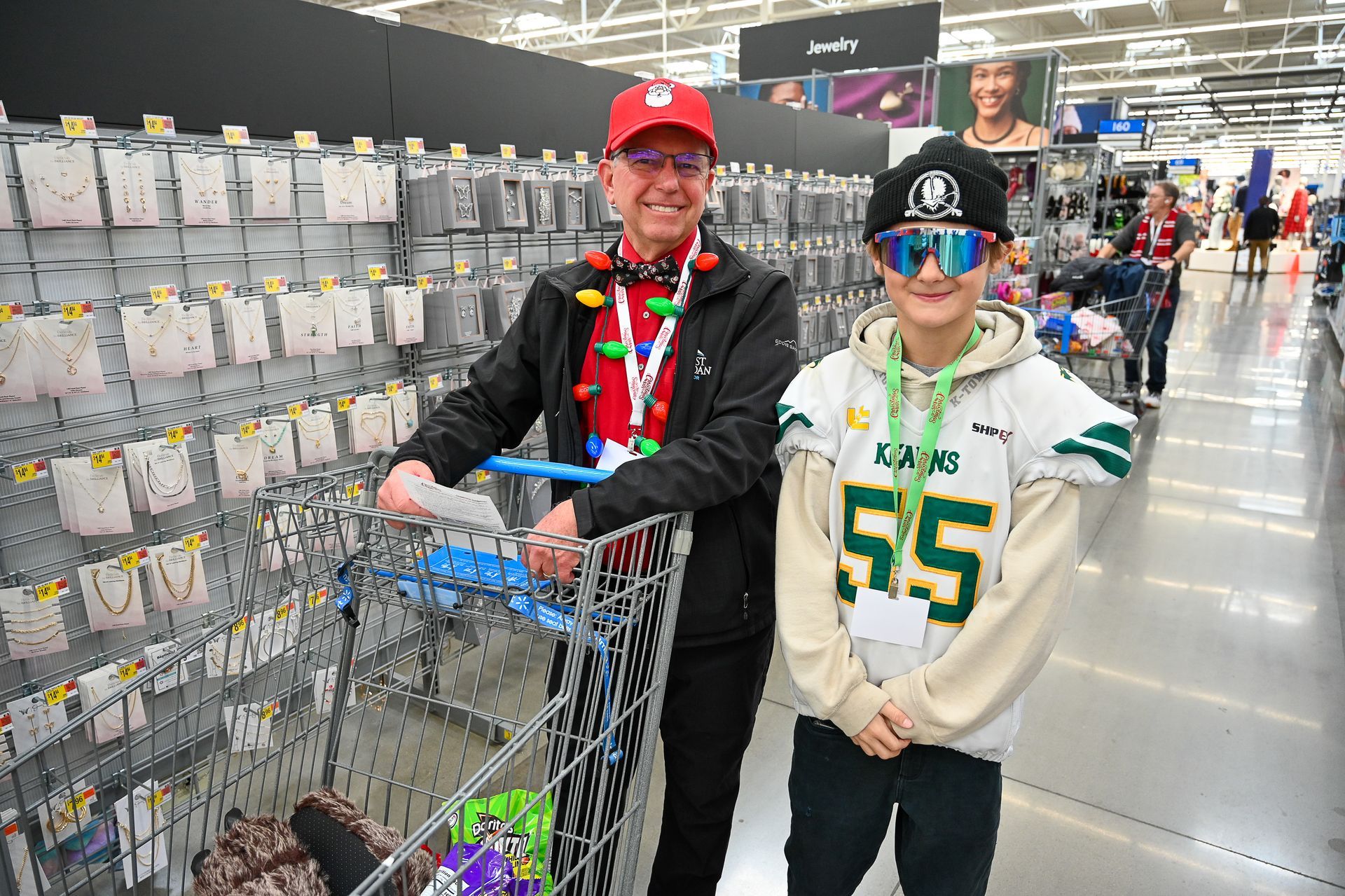 A man and a boy are standing next to each other in a shopping cart in a store.